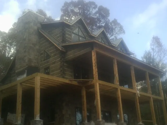 Stone chimney and dormers on a large log home with a timber porch in Charlotte